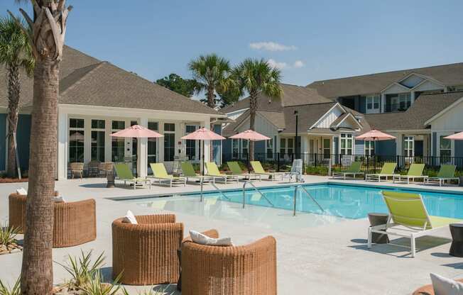 A pool area with chairs and umbrellas in front of a building.