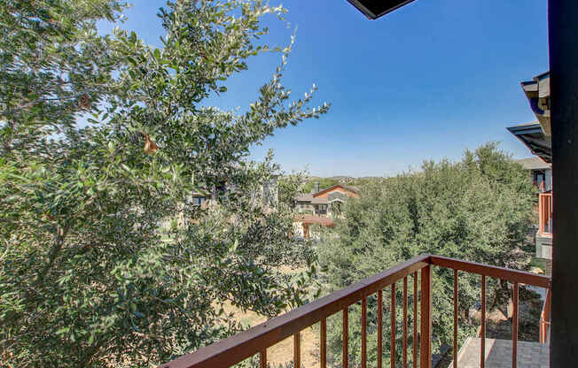 A balcony with a railing overlooks a tree-filled landscape.