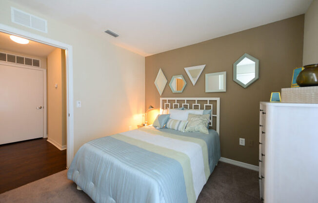 A bedroom with a bed, a dresser, and a mirror.