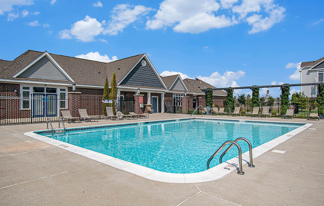 A swimming pool in front of a building with a fence around it at The Reserve at The Reserve at Destination Pointe in Grimes, IA 50111
