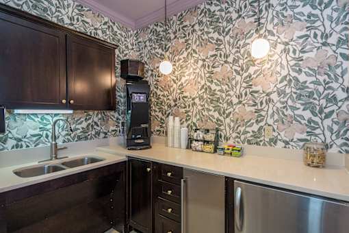 A kitchen with a wallpapered backsplash and a coffee maker.
