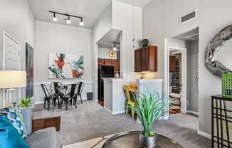 A living room with a grey sofa, a dining table and a painting on the wall.