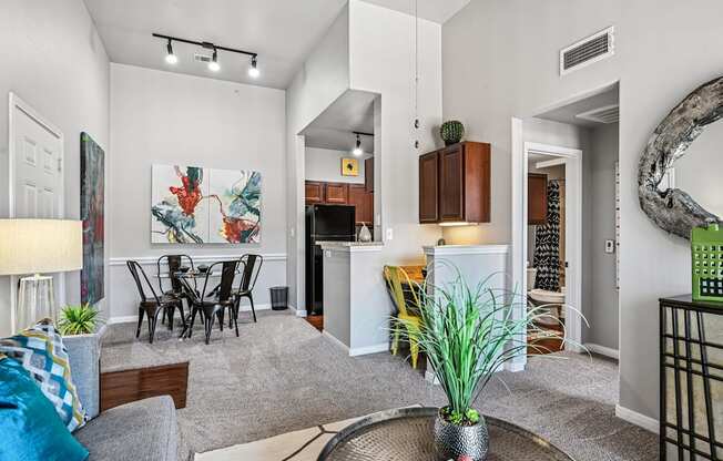 A living room with a grey sofa, a dining table and a painting on the wall.