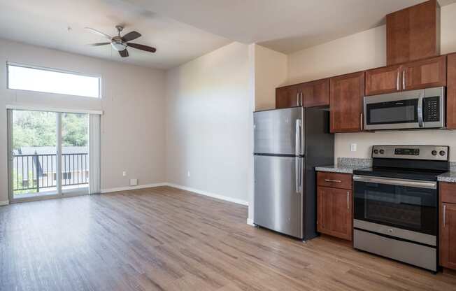 a kitchen and living room with wood floors and a sliding glass door leading to a balcony