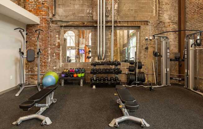 A gym with a variety of equipment including weights and a bench.