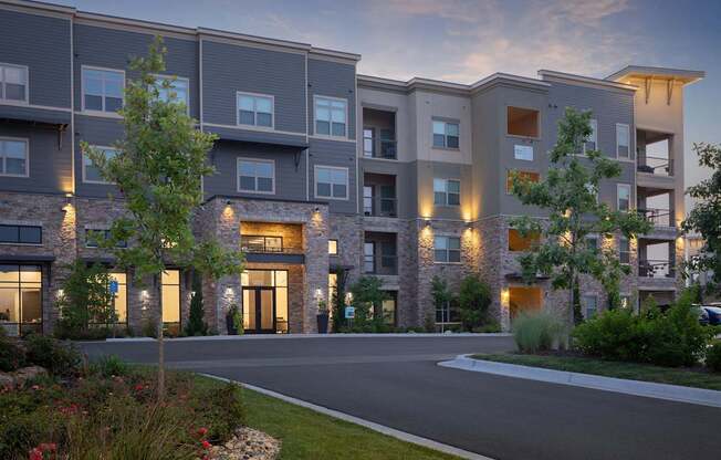 A modern apartment building with a driveway and landscaping in front.