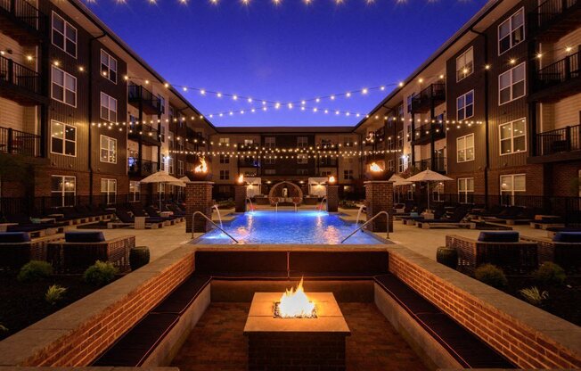 an outdoor pool with a fire pit at night