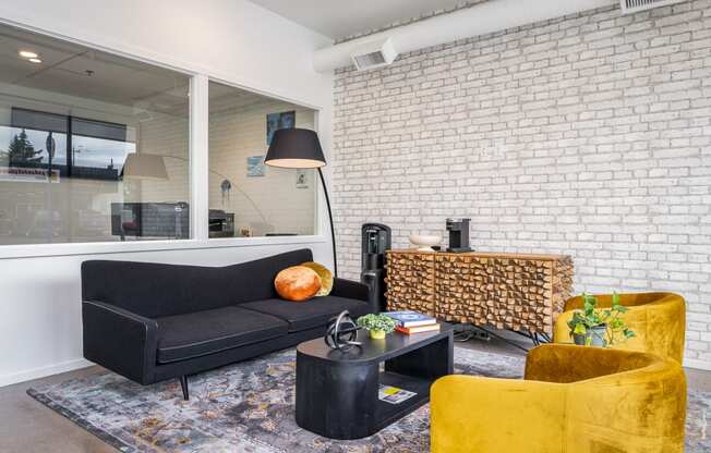 a living room with a black couch and yellow chairs