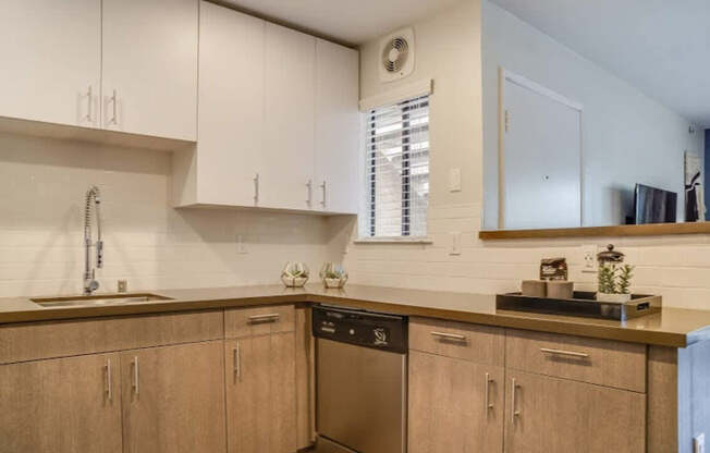 A kitchen with wooden cabinets and a stainless steel dishwasher.