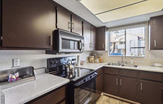 A kitchen with brown cabinets and a black stove top oven.