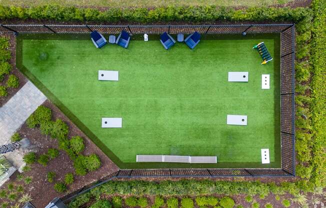 A green lawn with a white fence and blue chairs.