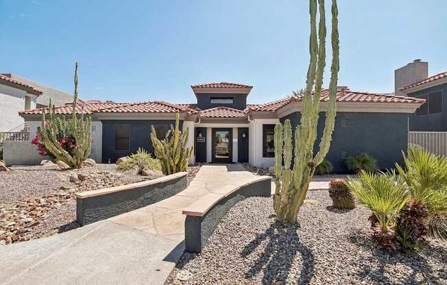 a house with a pathway and cactus in front of it