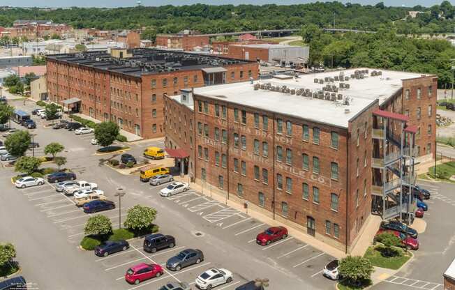 an aerial view of a brick building with cars parked in a parking lot