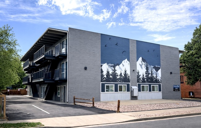 Contemporary apartment exterior with artistic mountain mural at Geneva Flats, featuring balconies and a serene atmosphere.