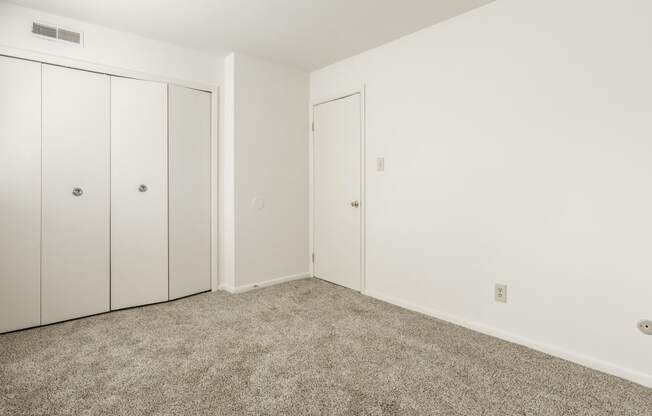 a bedroom with carpet and white walls and doors