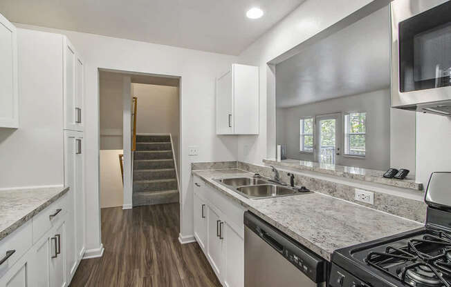 A kitchen with white cabinets and a breakfast bar at Foxwood and The Hermitage, Portage, MI, 49024