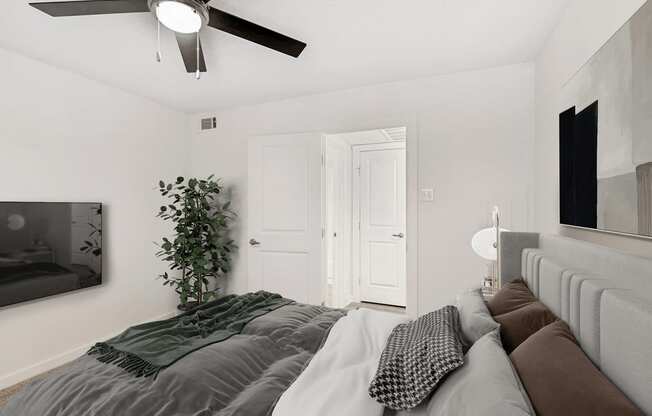 Virtually staged bedroom with wall mounted television, artificial tree, ceiling fan with light and wall art