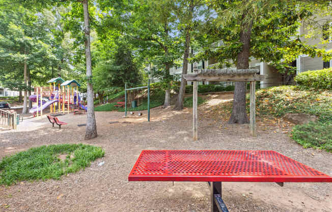 a park with a red picnic table and playground equipment