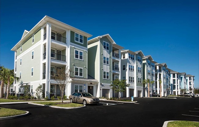 A row of modern apartment buildings with a car parked in front.