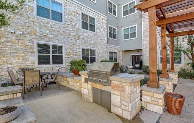 a backyard with a grill and a patio with a table and chairs