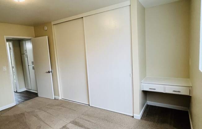 Carpeted bedroom with large closet and build in desk at Plaza Verde Apartments in Escondido, California.