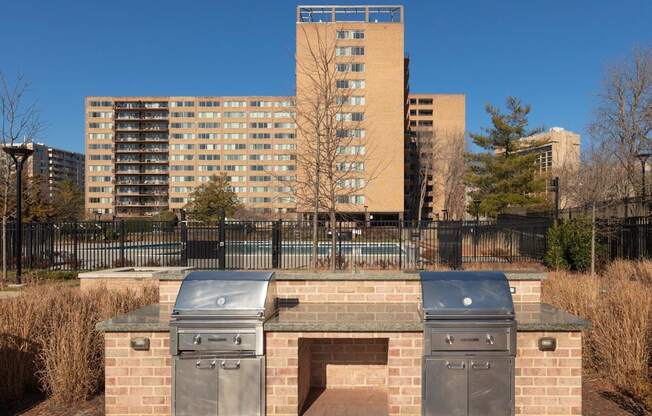 A brick structure with two ovens on top of it in front of a tall building.