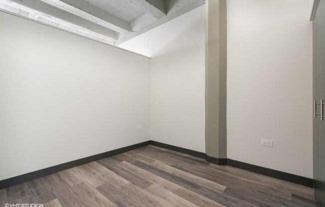 an empty room with wood floors and white walls