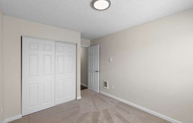 a bedroom with two doors, tan carpeted floor, and overhead lighting  at Park Edmonds Apartment Homes, Washington, 98026