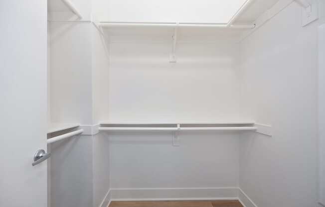 A white closet with a door and a shelf.