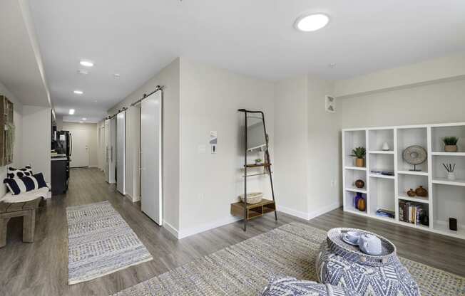 Apartment Living Area with Plank Flooring and cozy rugs, white bookshelf, and recessed lighting at Arabella Apartment Homes, Washington