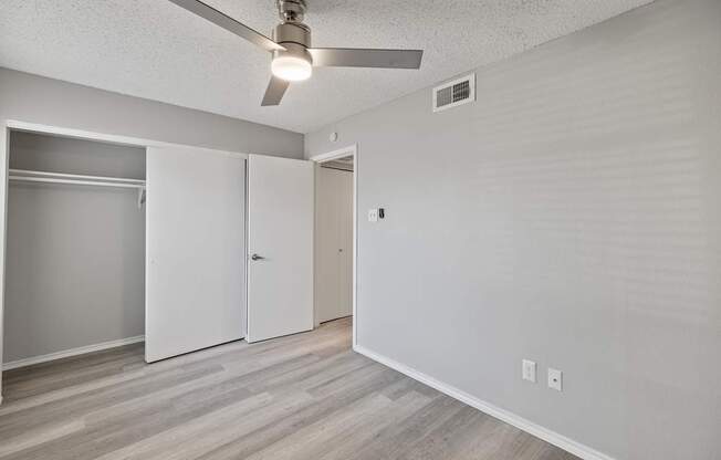 A room with a ceiling fan and a white door.