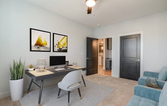 a living room with a desk with a computer and a couch