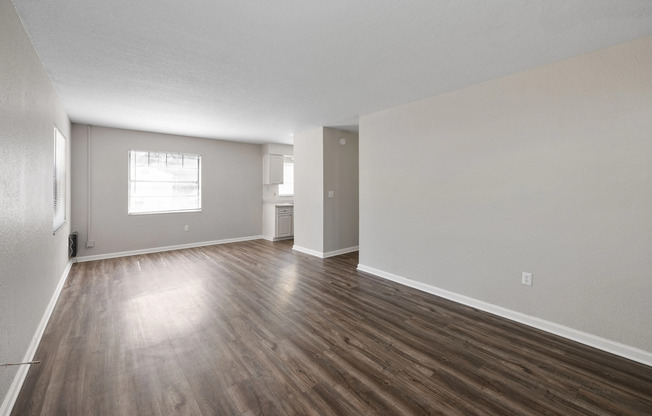 Spacious open-concept living area with natural light and sleek hardwood floors, perfect for modern living.