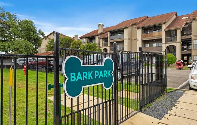 a gate with a green sign that says bark park on it