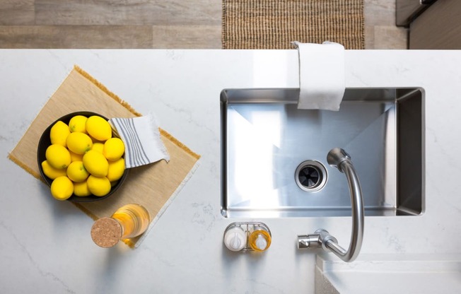 a bowl of lemons on a counter next to a sink
