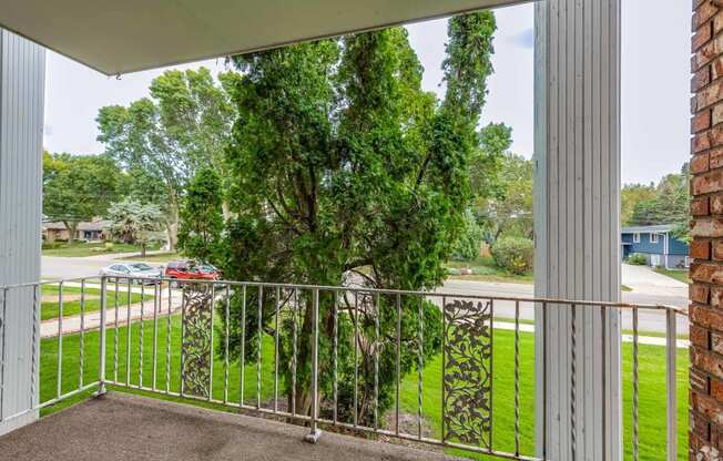 the view from the balcony of a home with a tree in the yard