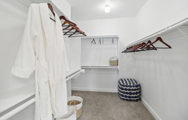 a white closet with a white robe and a stool