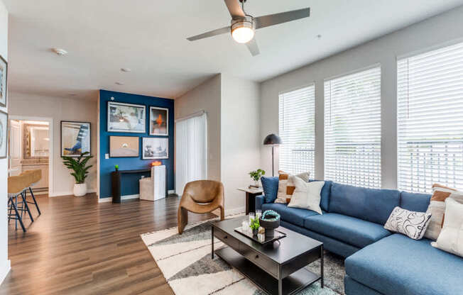 A living room with a blue couch and a wooden floor.