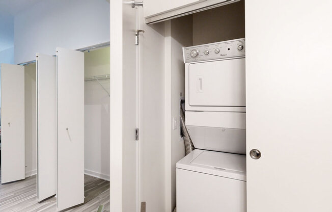 a white washer and dryer in a room with a bedroom in the background
