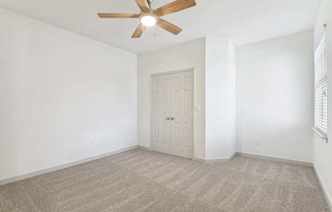 an empty living room with white walls and a ceiling fan