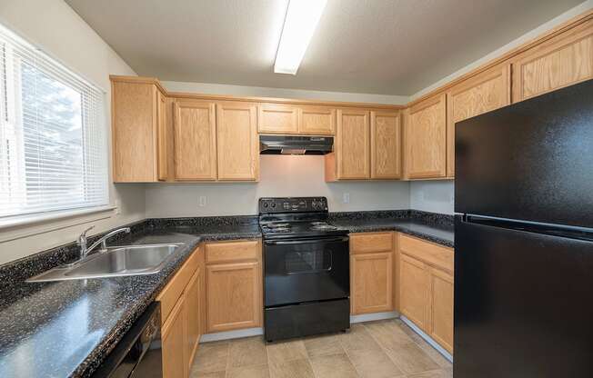 A kitchen with black appliances and wooden cabinets at Autumn Oaks Apartments, Roseville, CA, 95678