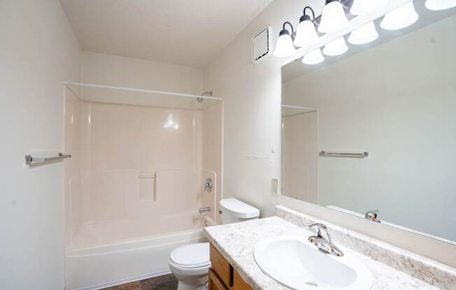 A white bathroom with a toilet, sink, and mirror.