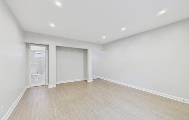 A large empty room with a doorway leading to a bathroom.