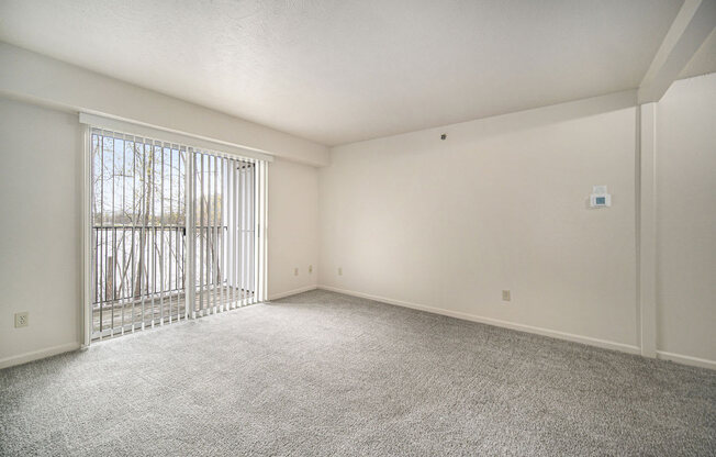 an empty living room with a sliding glass door to a balcony at Canal 2 Apartments in Lansing, MI