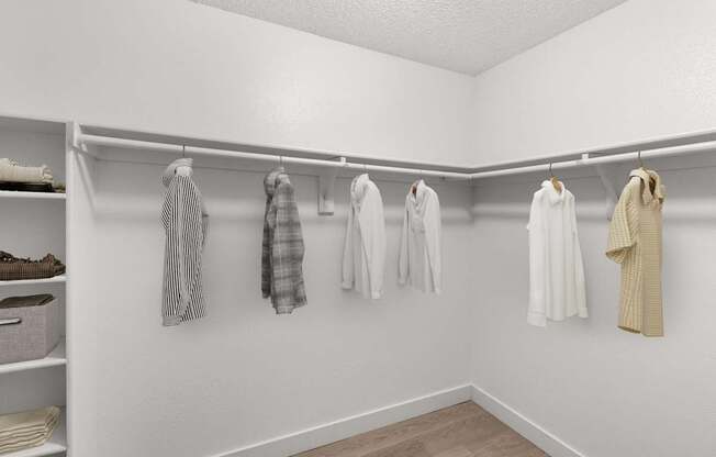 A white closet with clothes hanging on hangers.