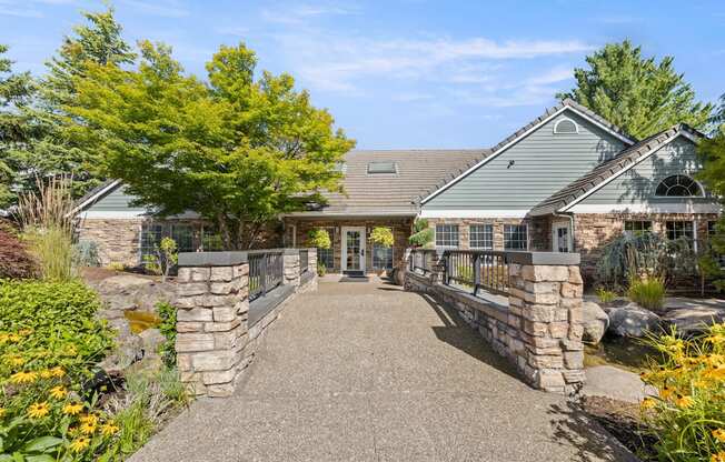A clubhouse with a stone wall and a bridge walkway at Clackamas Trails Apartments, Oregon, 97222