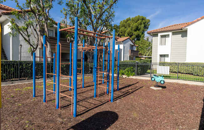 A playground with a blue and orange swing set.