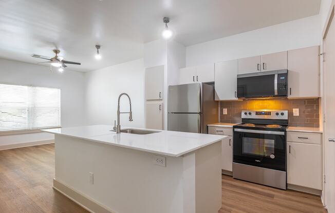 A modern kitchen with a white countertop and stainless steel appliances.