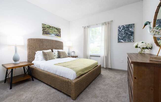A bedroom with a large bed and a wooden nightstand at The Palms at Chatham apartments in Savannah GA.