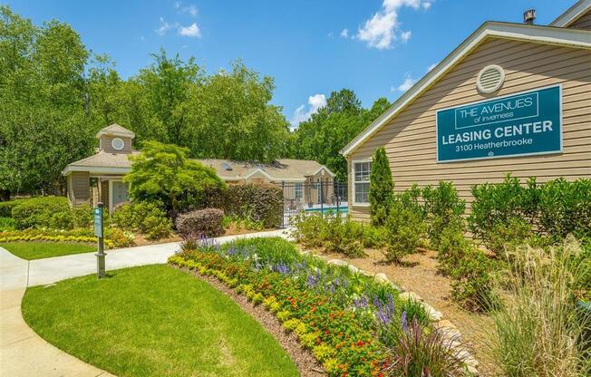 a garden in front of a building with a leasing center sign